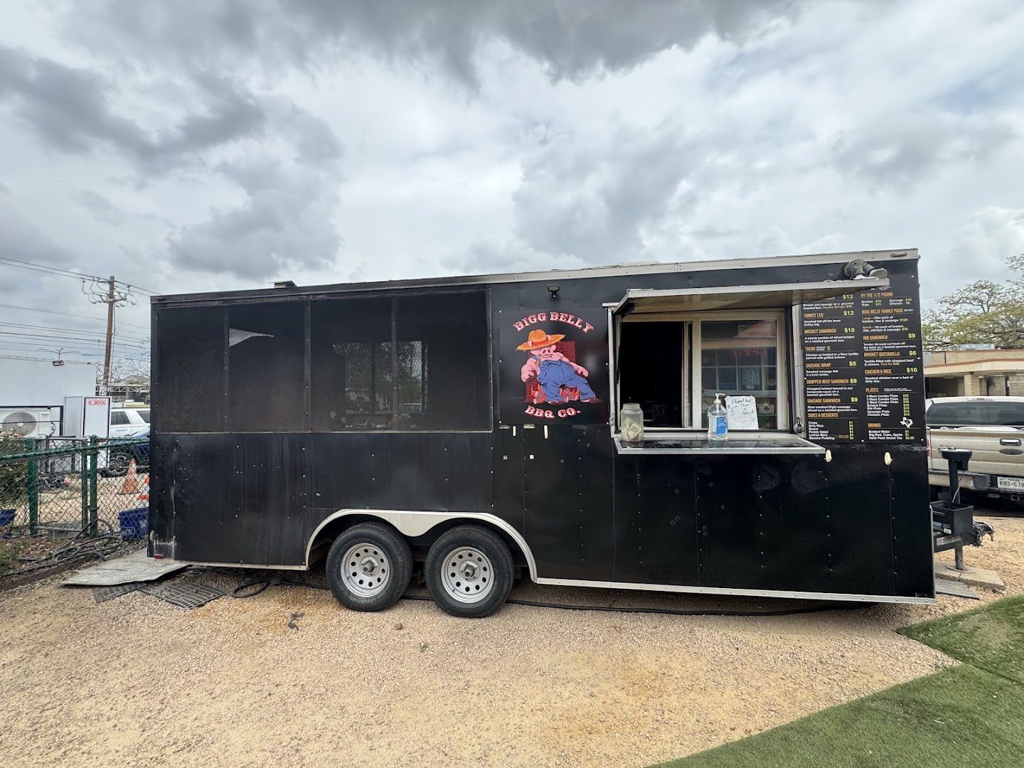 The full side of Bigg Belly BBQ Co. on a gravel lot with the serving window open