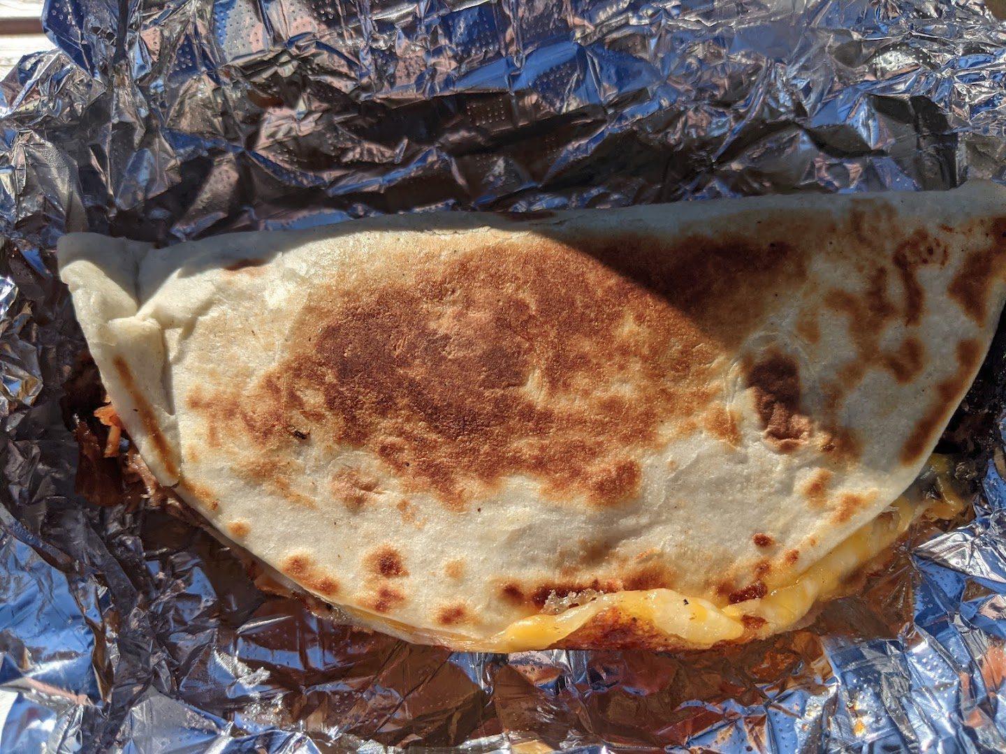 Pressed brisket quesadilla folded inside a foil wrapper