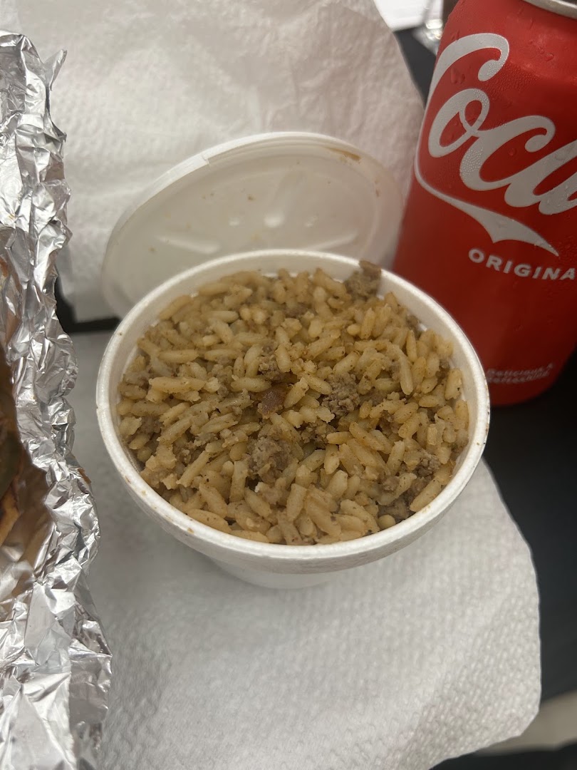 Dirty rice side dish in a foam cup next to a soda can